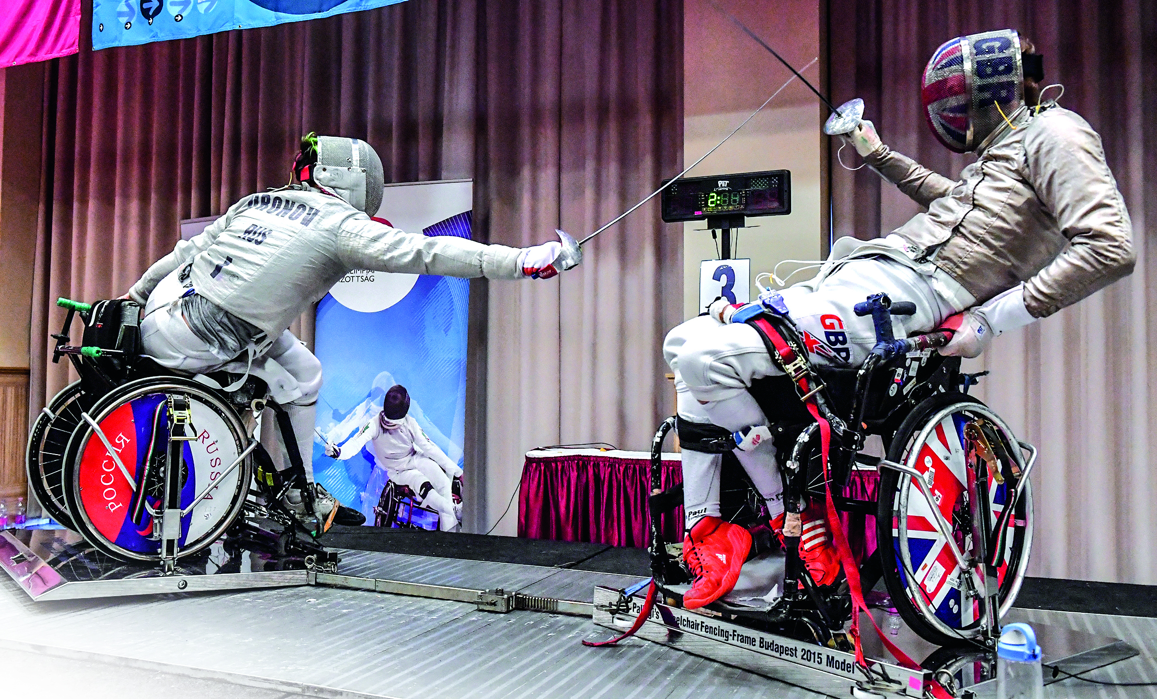 Two boys in fencing gear and modified wheelchair facing each other